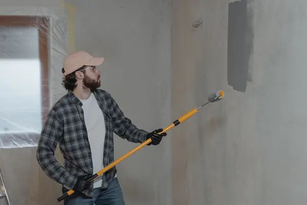 Painter rolling grey paint onto an interior wall in Chattanooga